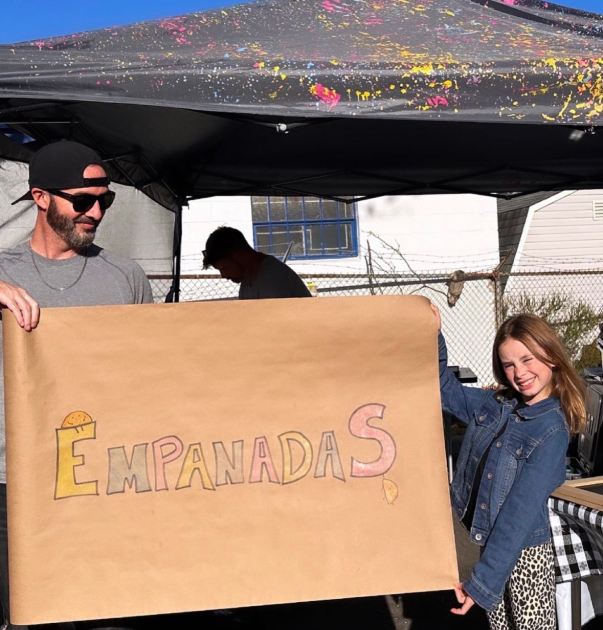 Michael and Charlotte holding the Empanadas banner at a pop-up